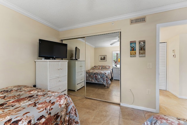 tiled bedroom featuring a closet, ornamental molding, and a textured ceiling