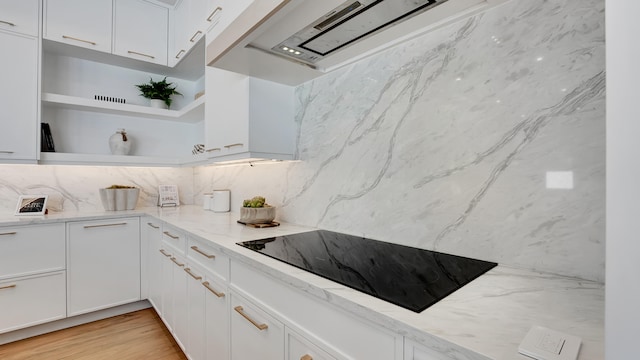 kitchen with black electric stovetop and white cabinetry