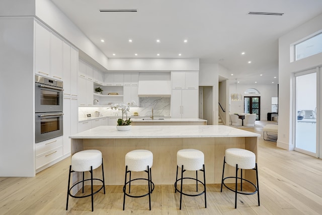 kitchen featuring light hardwood / wood-style floors, white cabinetry, and a center island with sink