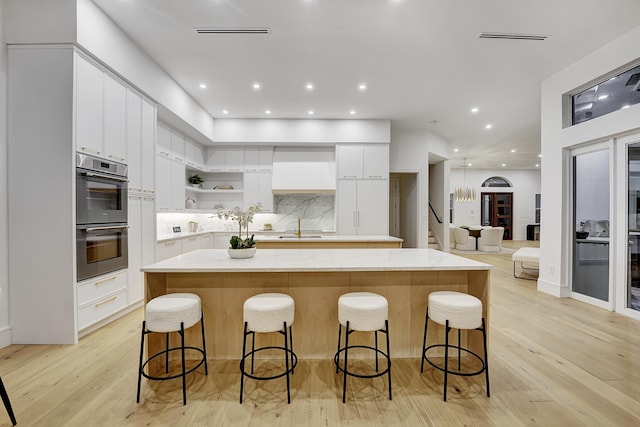 kitchen featuring a center island, white cabinets, light hardwood / wood-style flooring, and double oven