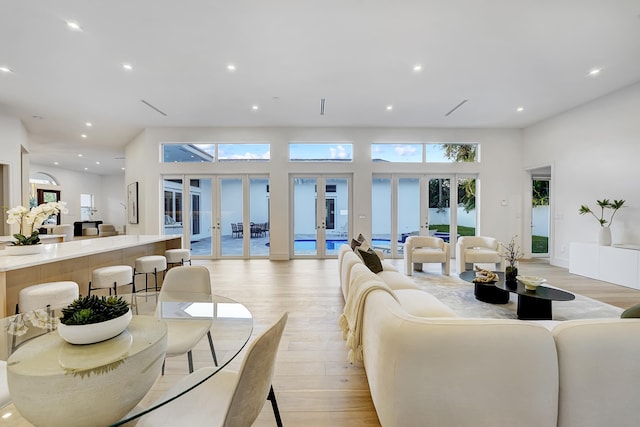 living room with light hardwood / wood-style floors, french doors, and a high ceiling