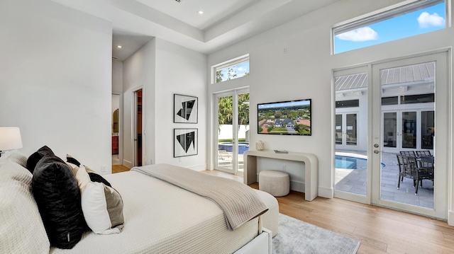 bedroom with light hardwood / wood-style floors, a high ceiling, and access to exterior