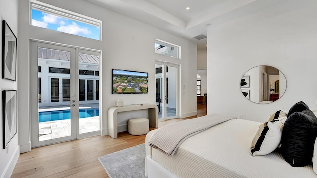 bedroom featuring a high ceiling, light wood-type flooring, access to outside, and french doors