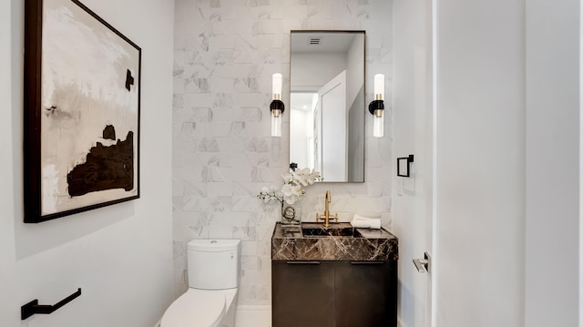 bathroom with tile walls, vanity, and toilet