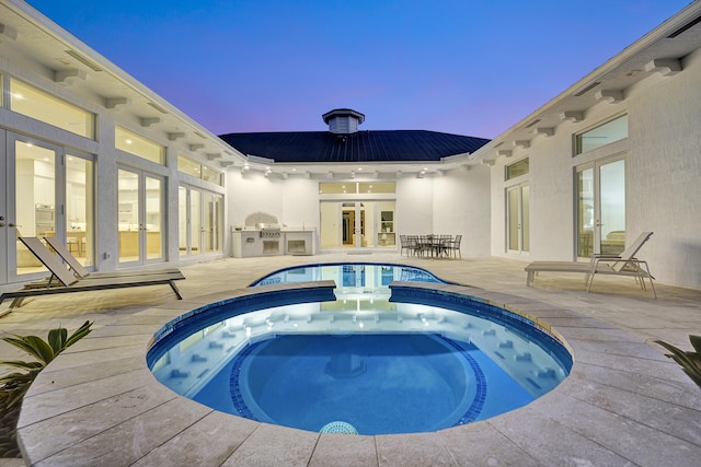 pool at dusk featuring french doors, a patio area, and an in ground hot tub