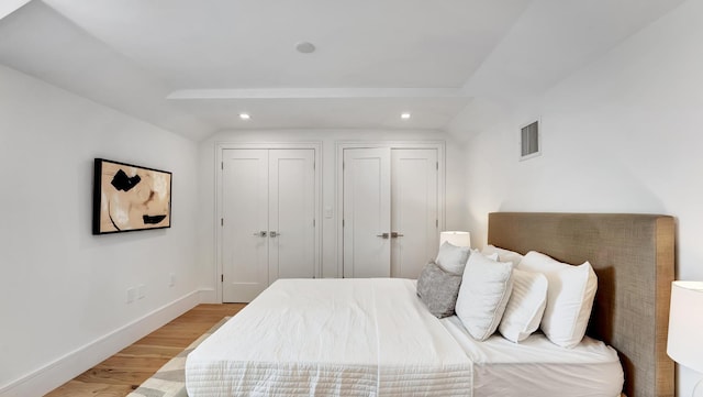 bedroom featuring light hardwood / wood-style floors and lofted ceiling