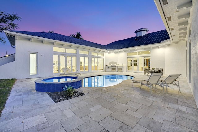 pool at dusk featuring an in ground hot tub, a patio, and french doors