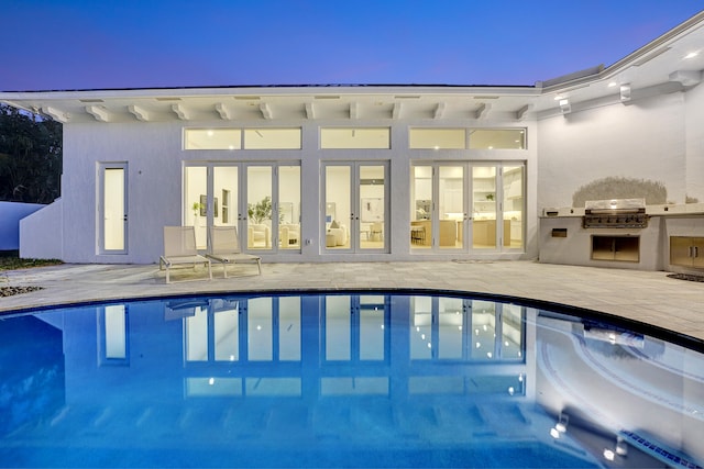 pool at dusk featuring a patio and area for grilling