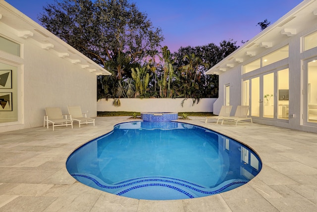 pool at dusk featuring a patio area