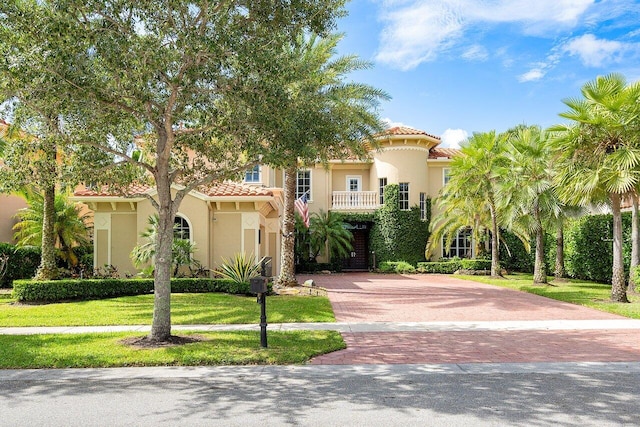 mediterranean / spanish home featuring a front lawn and a balcony