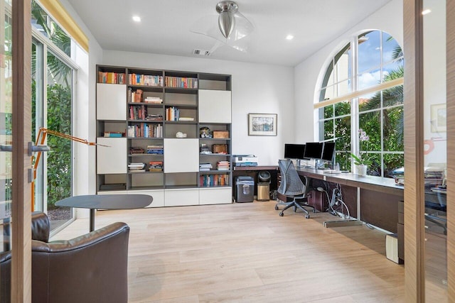 office with built in desk and light wood-type flooring