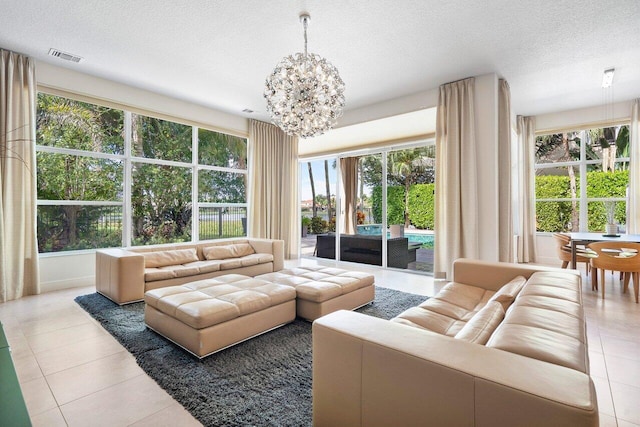 tiled living room featuring a healthy amount of sunlight, a textured ceiling, and a chandelier