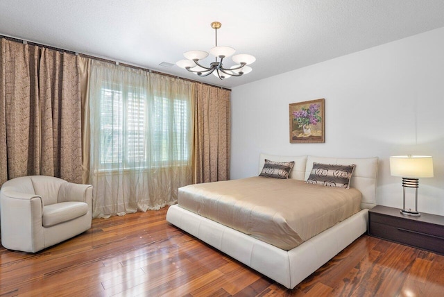 bedroom with a notable chandelier, a textured ceiling, and hardwood / wood-style floors