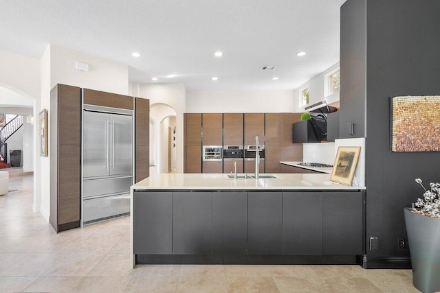 kitchen with sink, kitchen peninsula, a textured ceiling, and light tile patterned floors