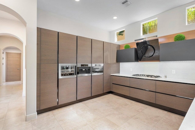 kitchen featuring stainless steel gas cooktop, decorative backsplash, and light tile patterned floors