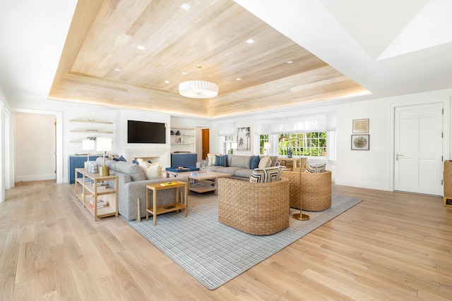 living room featuring light hardwood / wood-style flooring, built in features, a tray ceiling, and wooden ceiling