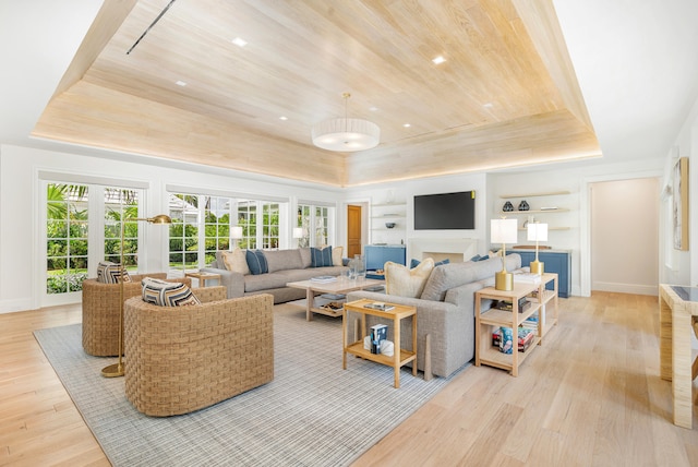 living room featuring light hardwood / wood-style flooring, wooden ceiling, a tray ceiling, and built in features