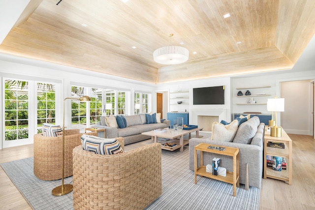 living room featuring light hardwood / wood-style floors, wood ceiling, built in features, and a raised ceiling