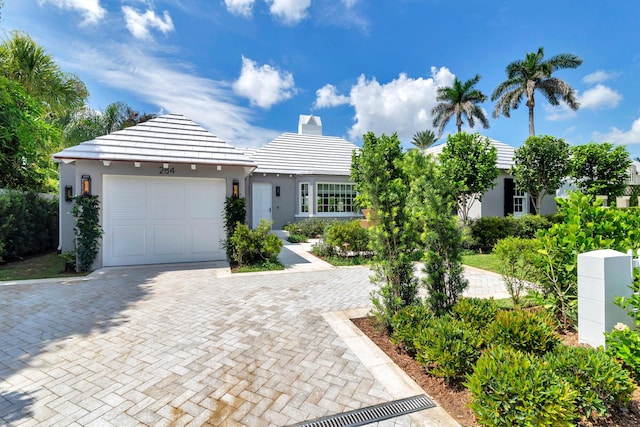 284 Monterey Rd, Palm Beach, FL 33480 - view of front of home with decorative driveway, stucco siding, a garage, a chimney, and a tiled roof