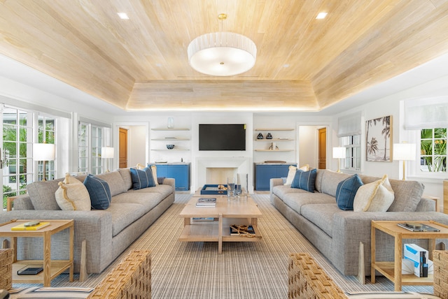 living room with wood ceiling, built in features, and a tray ceiling