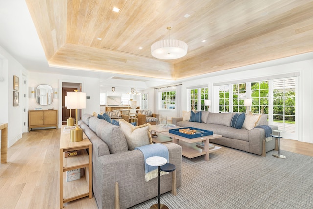 living room with light hardwood / wood-style flooring, wood ceiling, and a tray ceiling