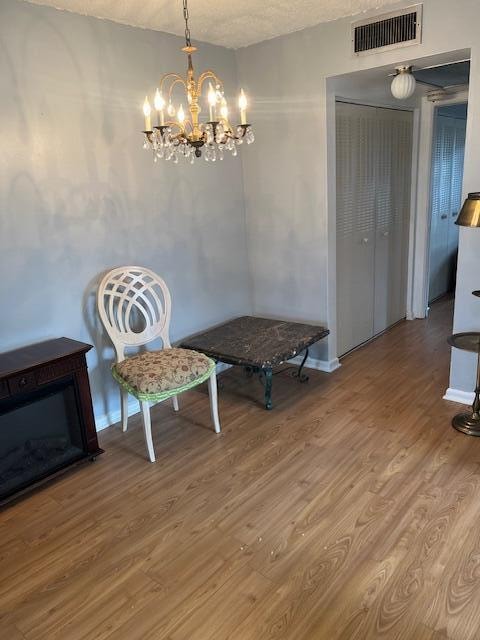 interior space with a textured ceiling, a notable chandelier, and hardwood / wood-style flooring