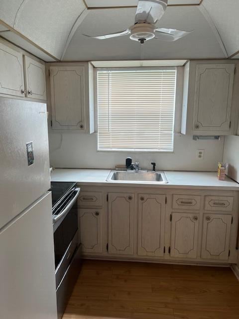 kitchen with light hardwood / wood-style floors, sink, white refrigerator, and stainless steel range