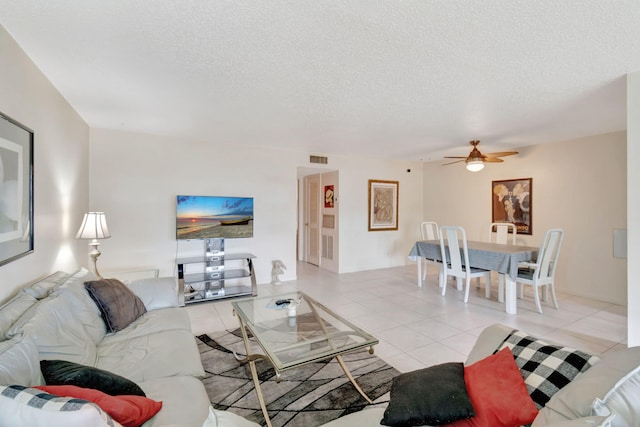 tiled living room with a textured ceiling and ceiling fan