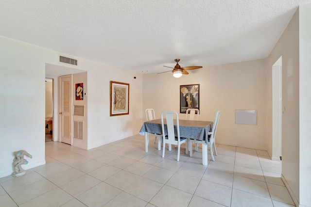 dining space featuring ceiling fan, light tile patterned floors, and a textured ceiling