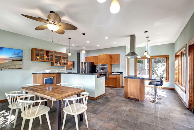 kitchen featuring island exhaust hood, appliances with stainless steel finishes, hanging light fixtures, and a center island