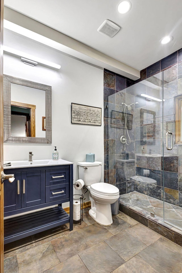 bathroom featuring vanity, toilet, and a shower with door