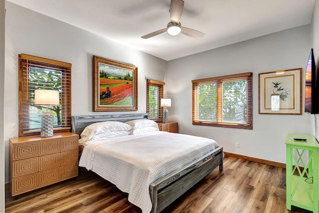 bedroom with ceiling fan, wood-type flooring, and multiple windows