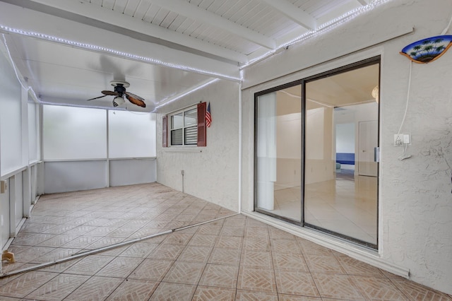 unfurnished sunroom with beam ceiling and ceiling fan