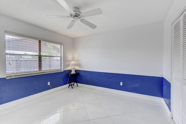 tiled empty room featuring ceiling fan