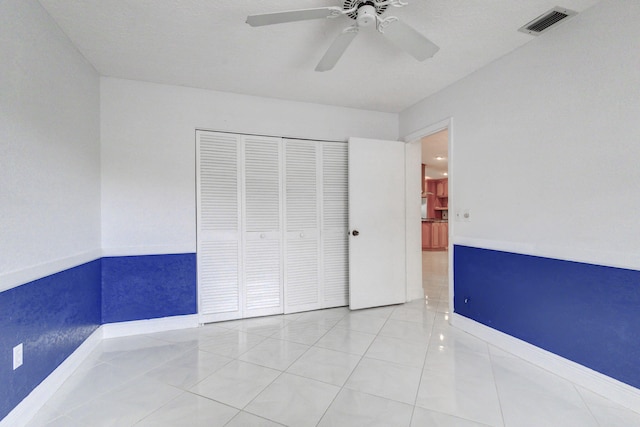 unfurnished bedroom featuring light tile patterned floors, a textured ceiling, a closet, and ceiling fan