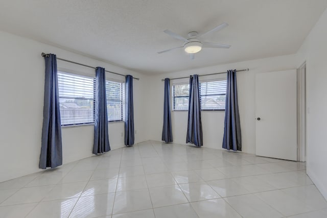 tiled spare room with a textured ceiling, a healthy amount of sunlight, and ceiling fan