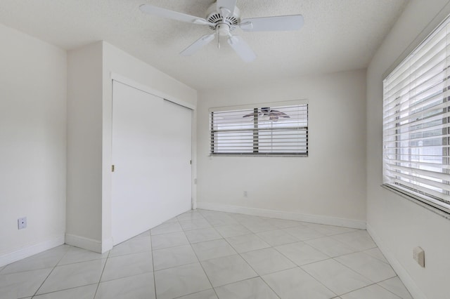 unfurnished bedroom featuring a closet, a textured ceiling, light tile patterned floors, and ceiling fan