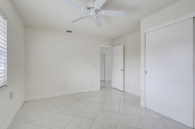 unfurnished room with a textured ceiling, light tile patterned floors, and ceiling fan