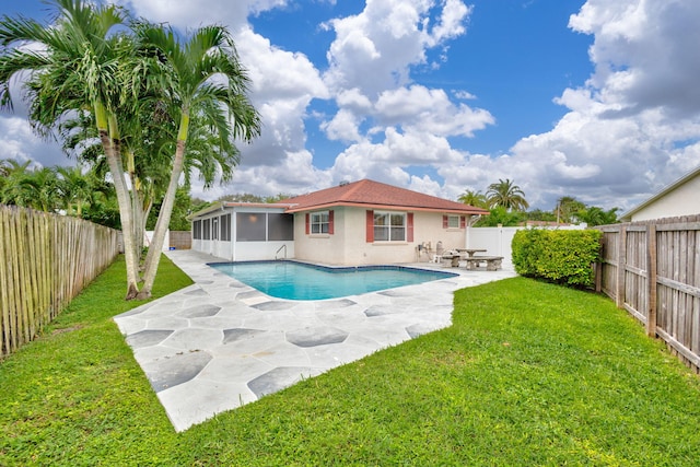 view of swimming pool featuring a patio, a yard, and a sunroom