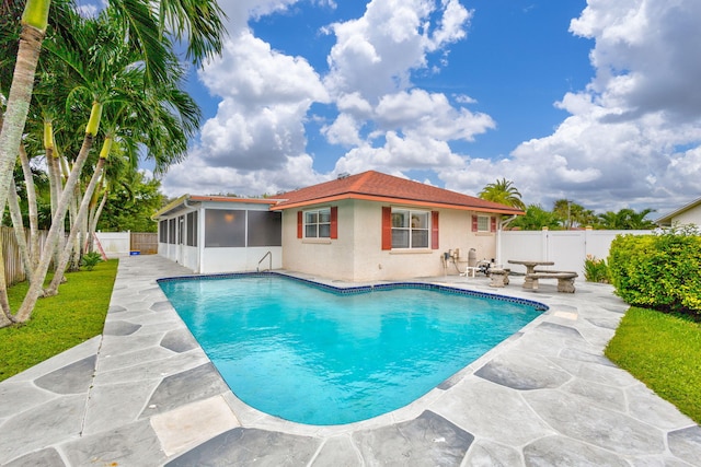 view of swimming pool with a sunroom and a patio area