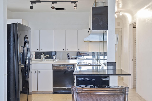 kitchen with sink, black appliances, range hood, white cabinetry, and light tile patterned flooring