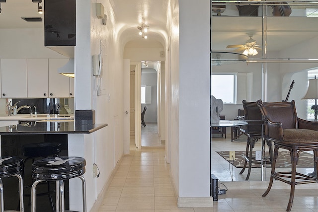 kitchen with light tile patterned floors, backsplash, white cabinetry, and ceiling fan