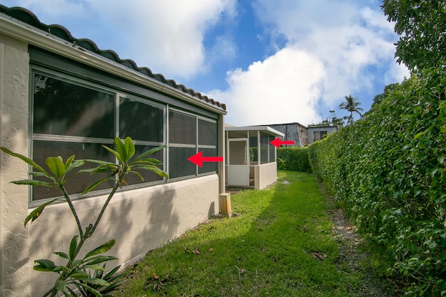 view of home's exterior with a yard and a sunroom