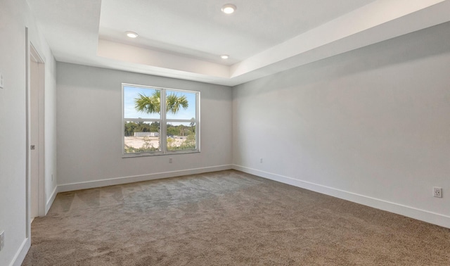 empty room with a tray ceiling and carpet flooring