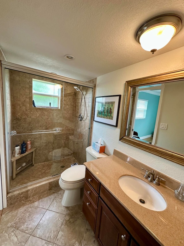 bathroom with a textured ceiling, toilet, walk in shower, vanity, and tile patterned flooring