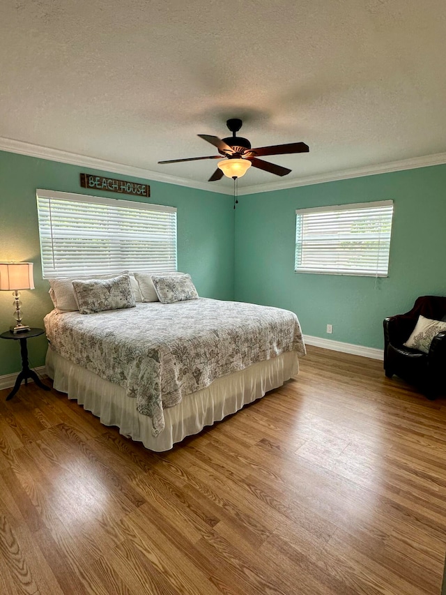 bedroom featuring crown molding, hardwood / wood-style flooring, a textured ceiling, and ceiling fan