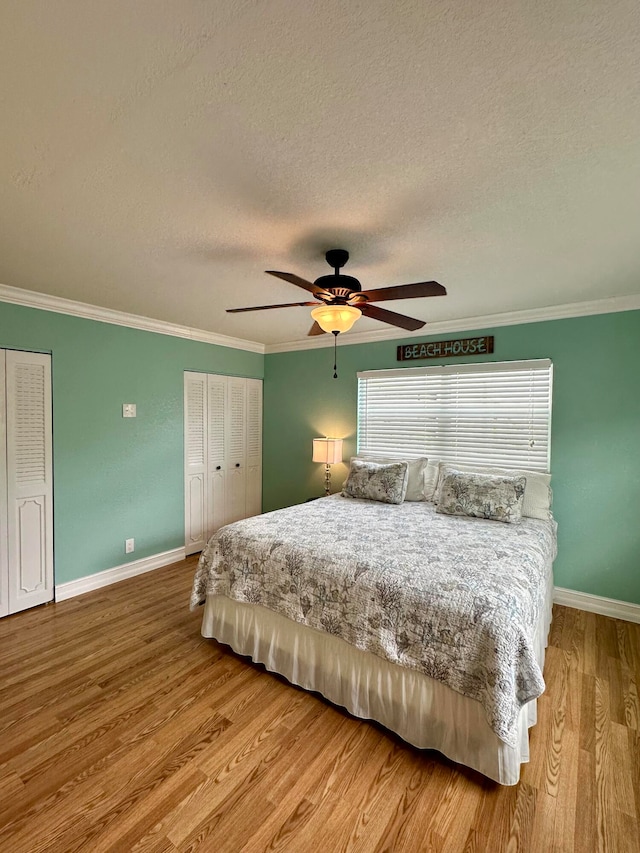 bedroom with ornamental molding, light hardwood / wood-style flooring, a textured ceiling, and ceiling fan