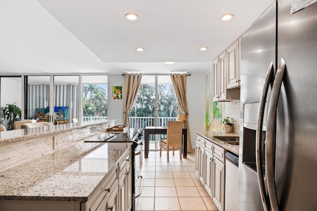 kitchen featuring light stone countertops, appliances with stainless steel finishes, light tile patterned floors, and cream cabinets