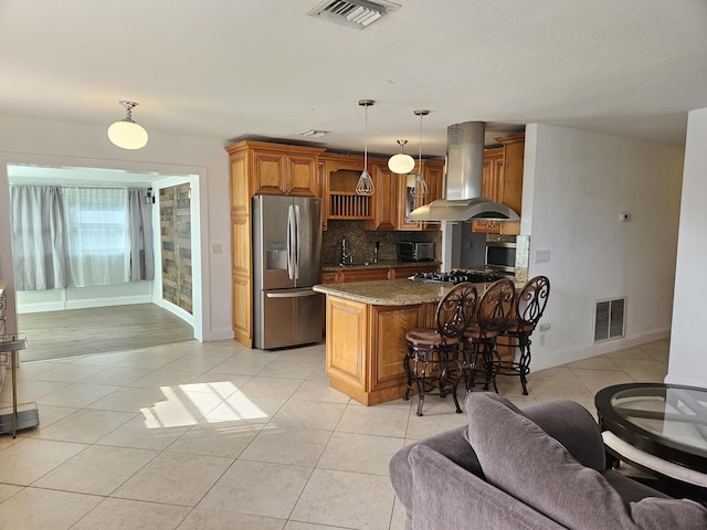 kitchen featuring hanging light fixtures, dark stone countertops, appliances with stainless steel finishes, island range hood, and a kitchen bar