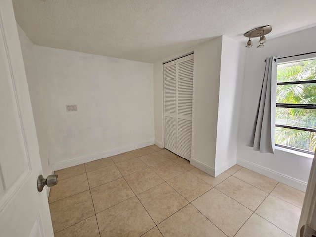 unfurnished bedroom featuring light tile patterned floors, a textured ceiling, and a closet